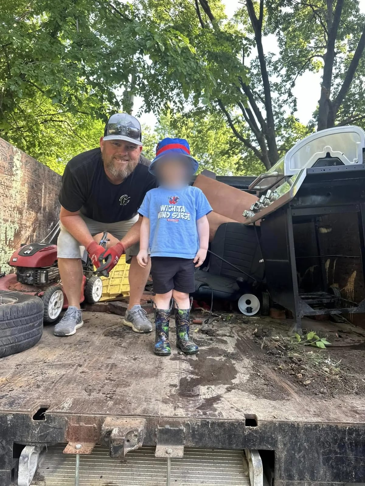 Dan Porter, owner and founder of A Plus Junk Removal KC, in the bed of the truck with a young child