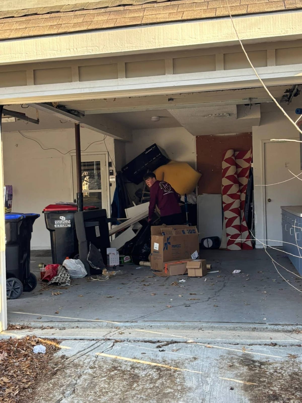 A Plus crew member clearing furniture, boxes and rugs out of a garage